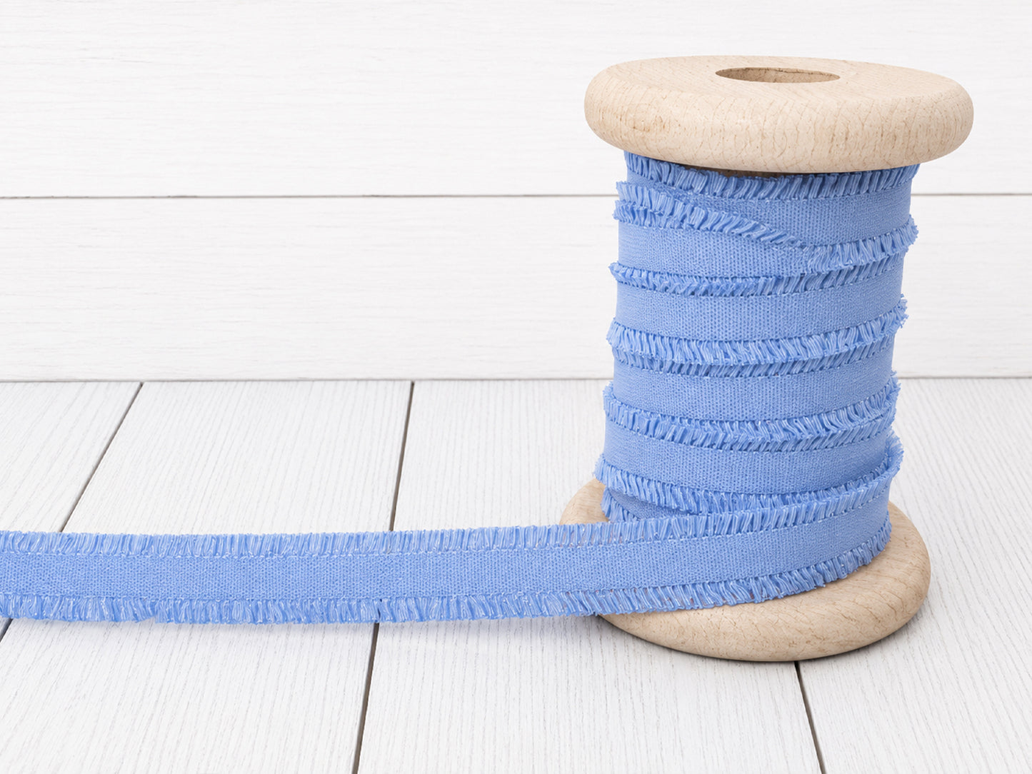 hellblau rüschen gummiband auf einer Holzspule, ideal für Nähprojekte und Verzierungen.