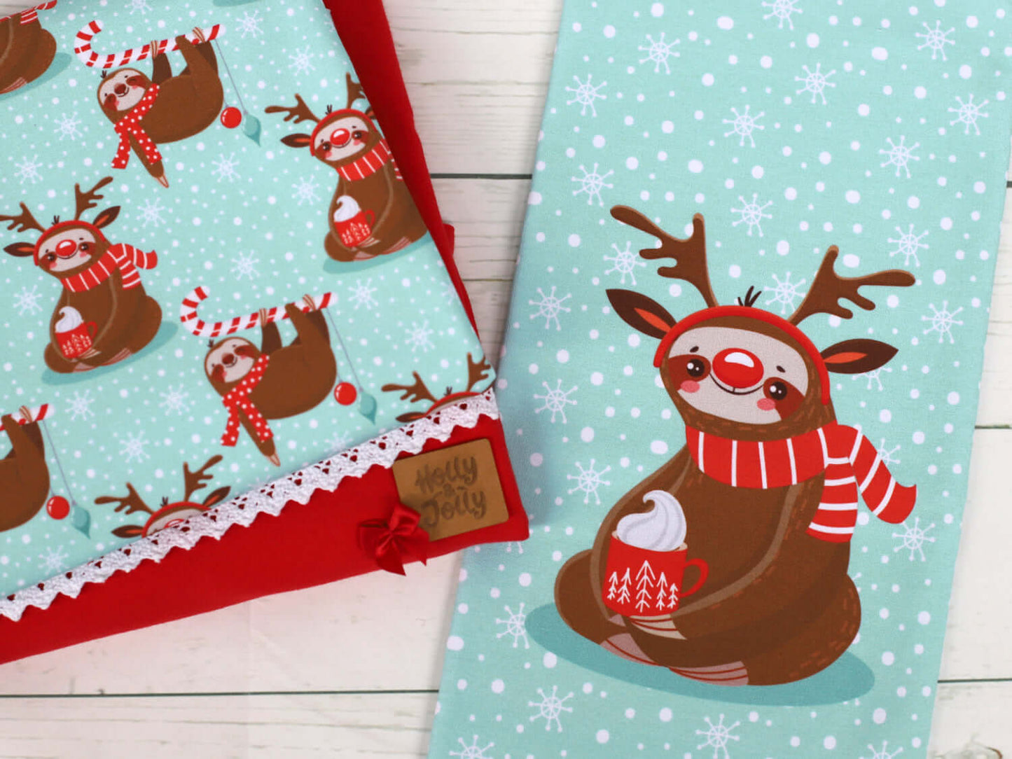 Merry Slothmas fabric Panel mit einem Gaultier auf Kakao, umgeben mit festlichen Rehntiermustern in Rot und Grün.