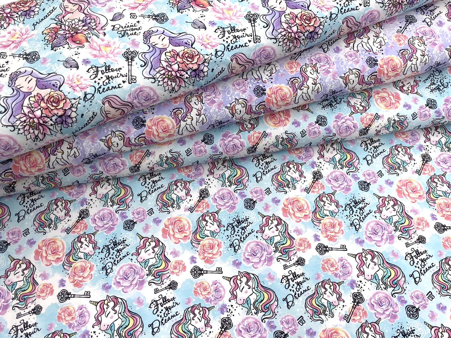 Jersey Stoff - Follow your Dreams - Prinzessin, helltürkis mit bunten Prinzessinnen und Blumen auf hellblauem Hintergrund.