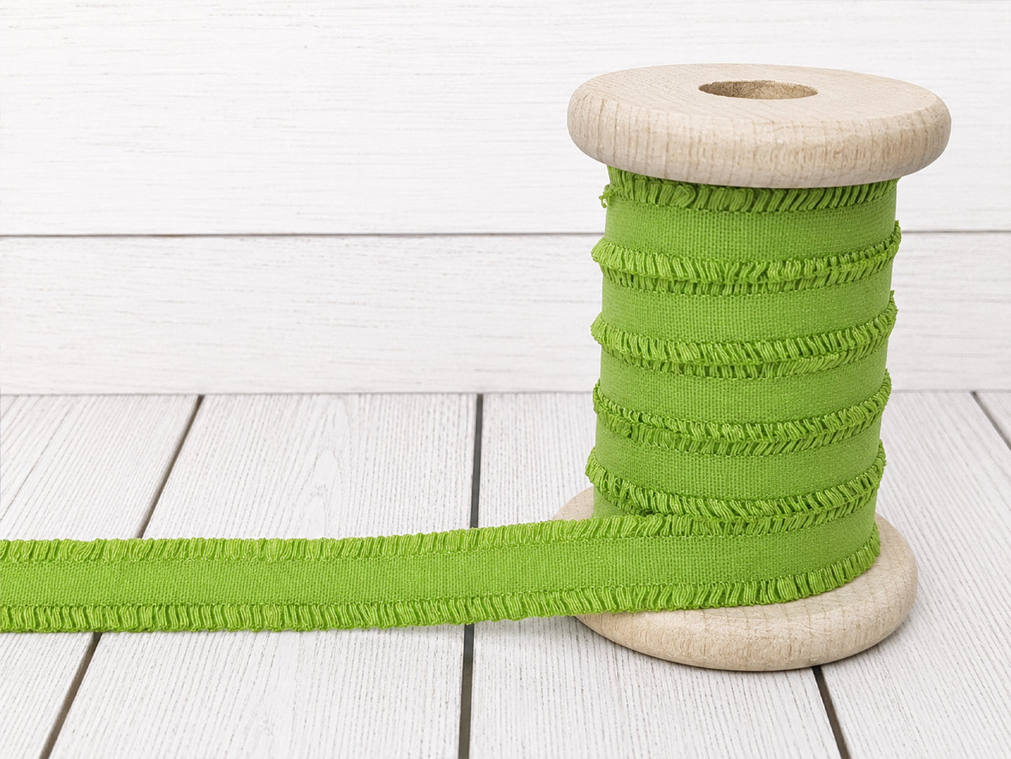 Rüschen Gummiband apfelgrün kaufen auf einer Holzspule abgebildet mit feiner Rüschenstruktur.