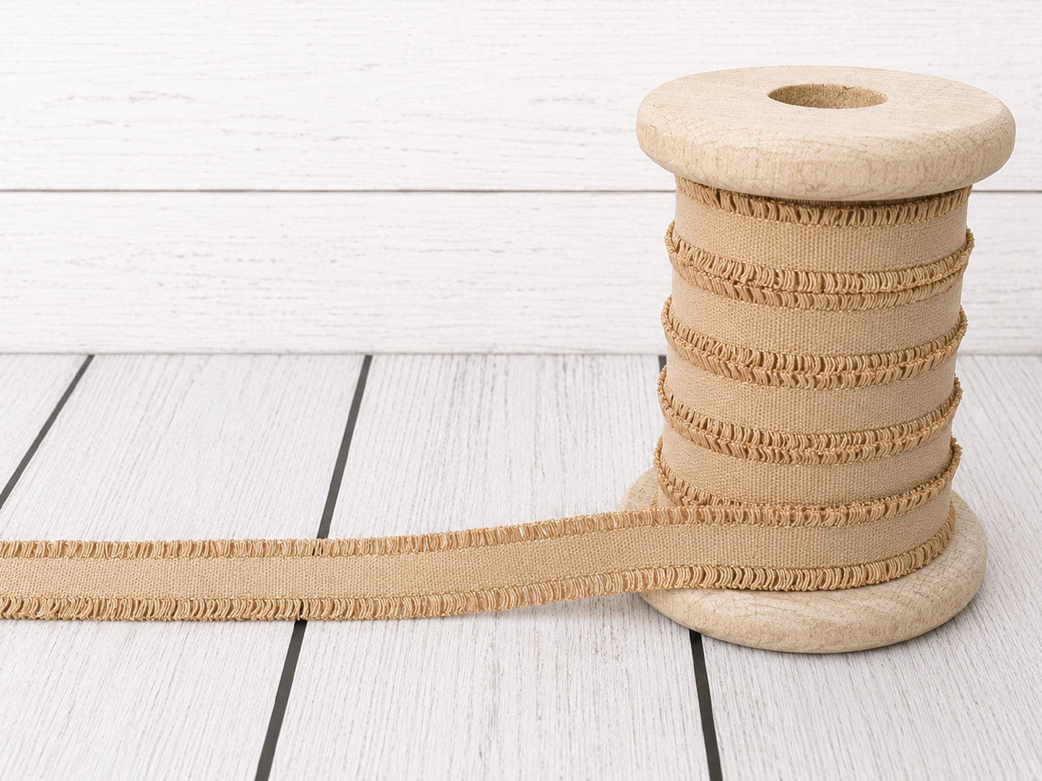 Beige Rüschen Gummiband auf einer Holzspule für kreative Nähprojekte, Breite ca. 14 mm.