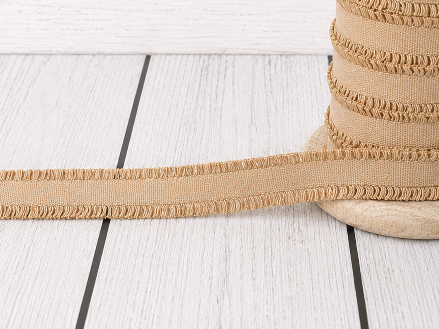 Beige Rüschen Gummiband auf einer Spule, ideal für kreative Nähprojekte und Verzierungen.