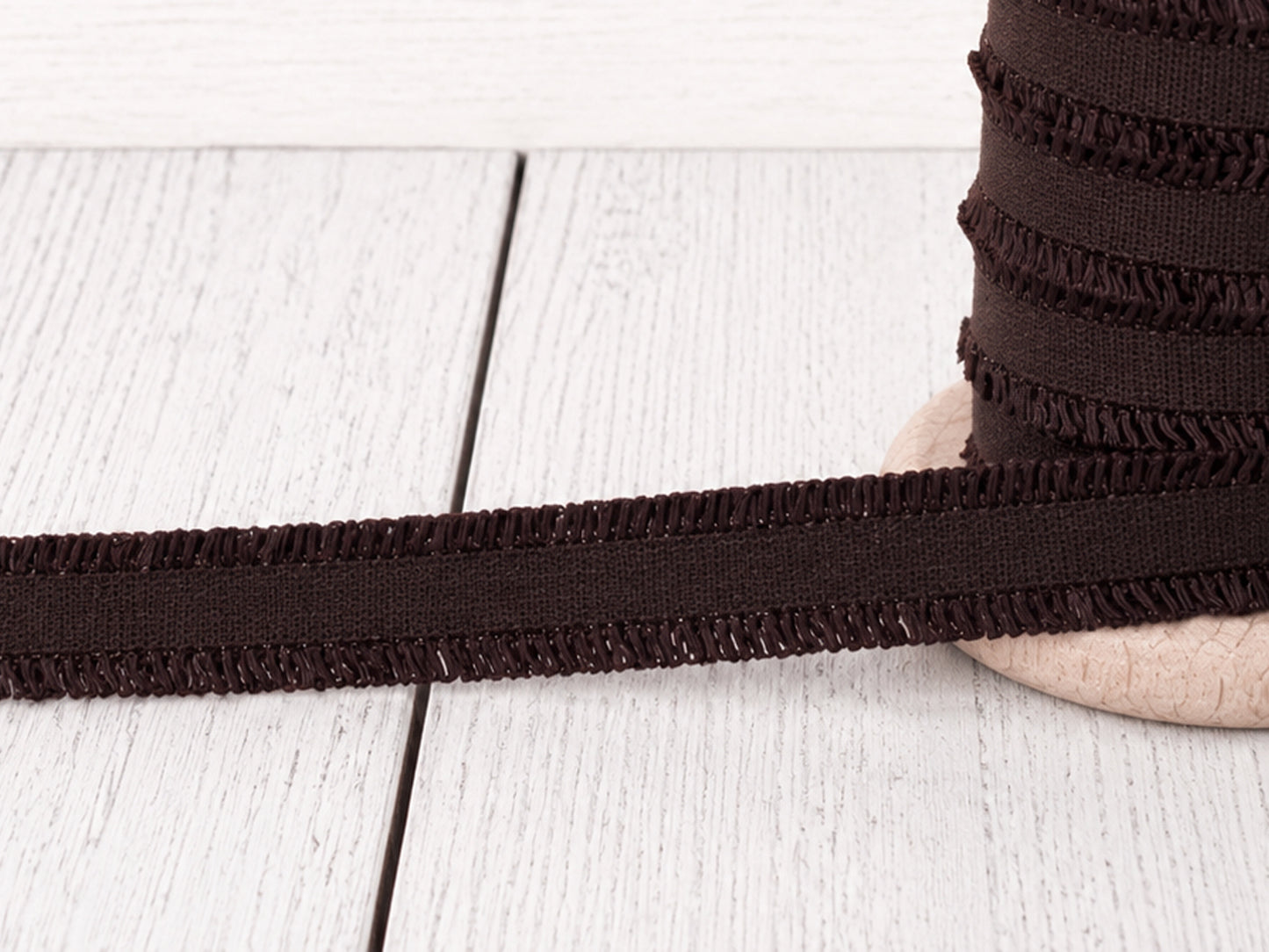 dunkelbraunes Rüschen Gummiband auf Holzuntergrund, perfekt für Nähprojekte und Verzierungen.