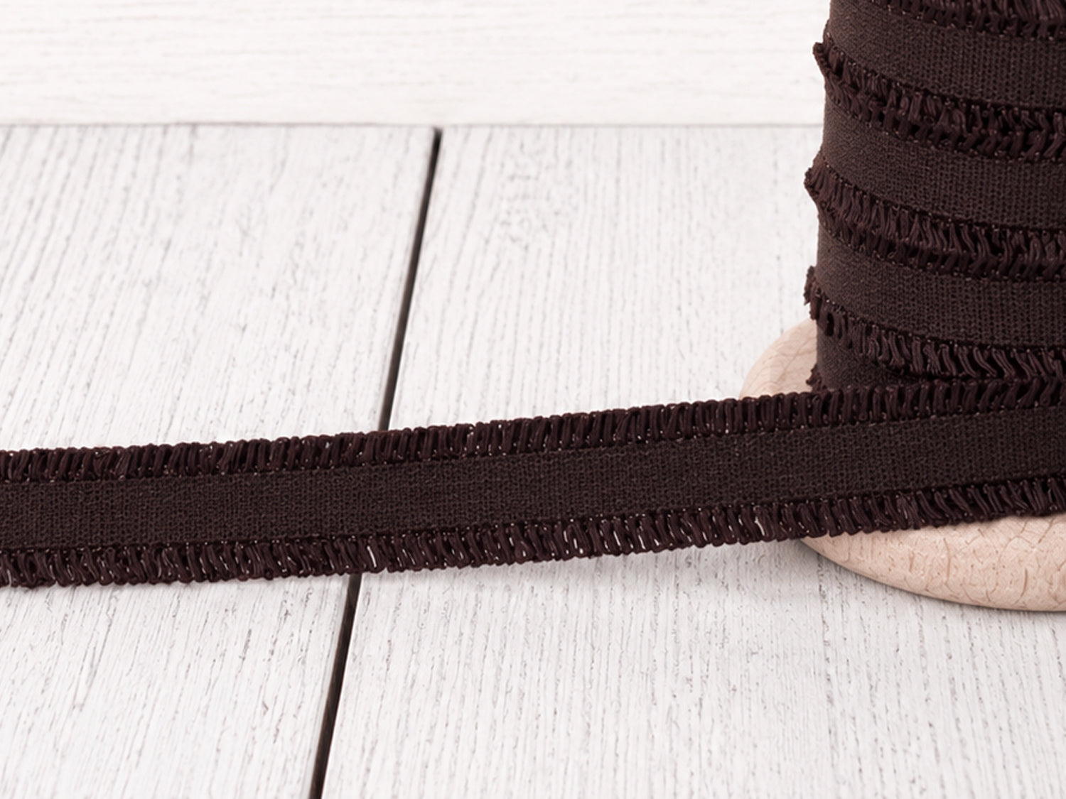 dunkelbraunes Rüschen Gummiband auf Holzuntergrund, perfekt für Nähprojekte und Verzierungen.