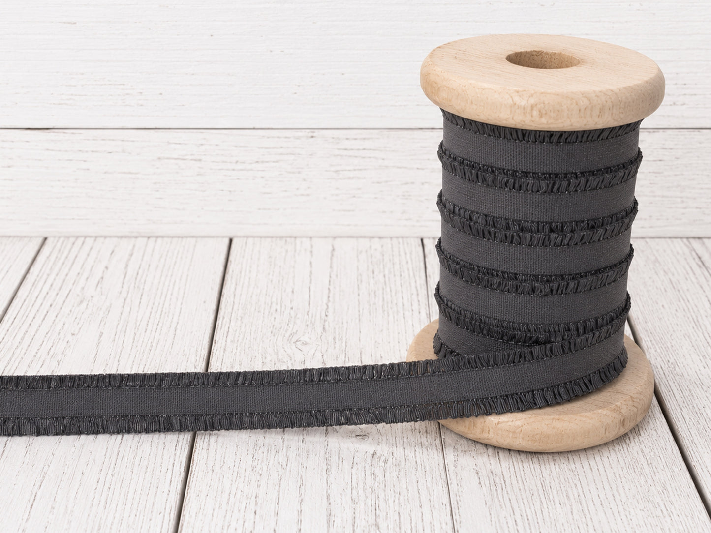 dunkelgrau rüschen gummiband auf einer Holzspule, ideal für Nähprojekte und Verzierungen.