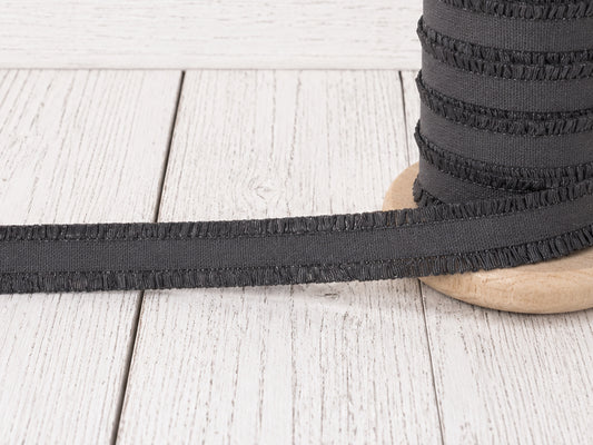 dunkelgrau rüschen gummiband auf einer Holzspule, perfekt für kreative Nähprojekte.