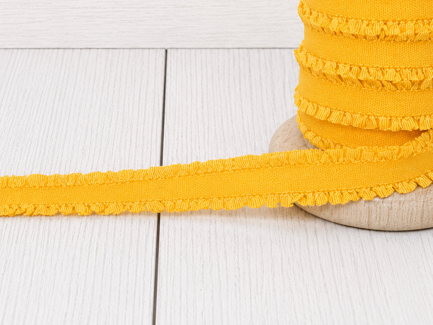 gelbes Rüschen Gummiband auf Holzunterlage, ideal für Nähprojekte und Verzierungen