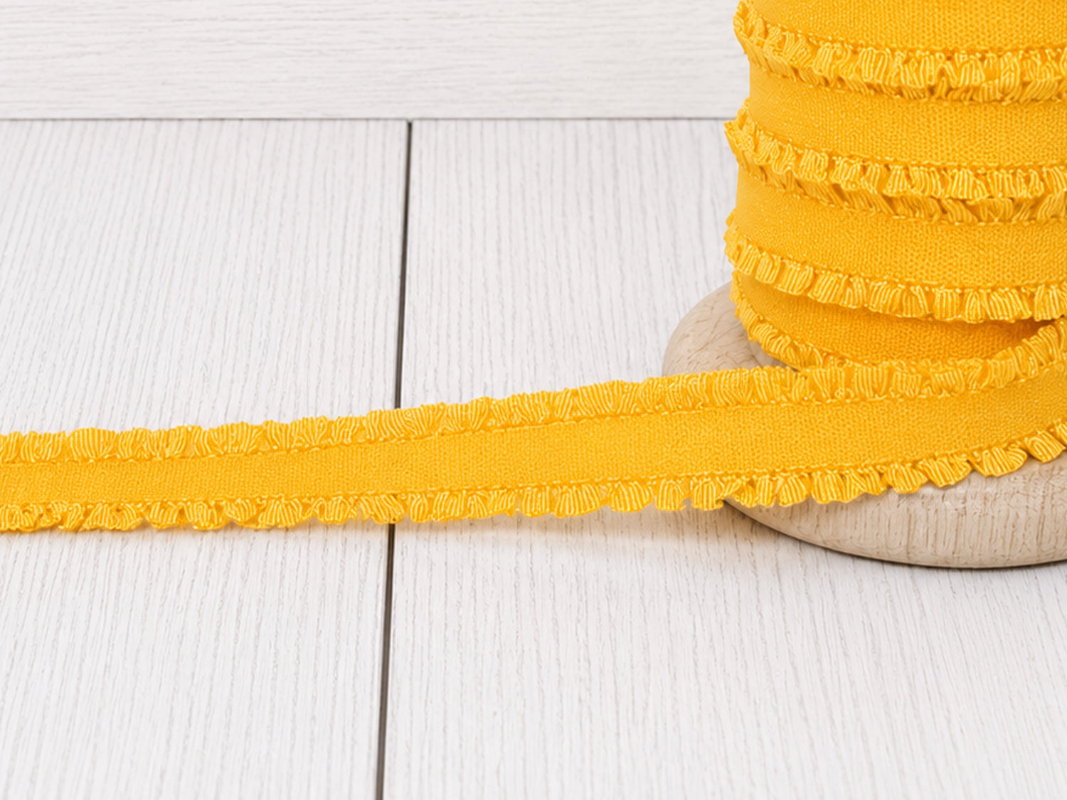 gelbes Rüschen Gummiband auf Holzunterlage, ideal für Nähprojekte und Verzierungen