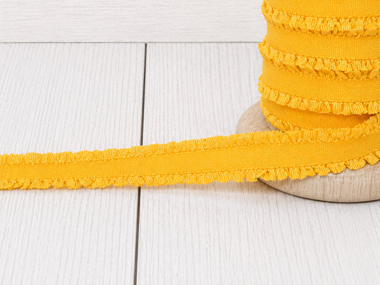 gelbes Rüschen Gummiband auf Holzunterlage, ideal für Nähprojekte und Verzierungen