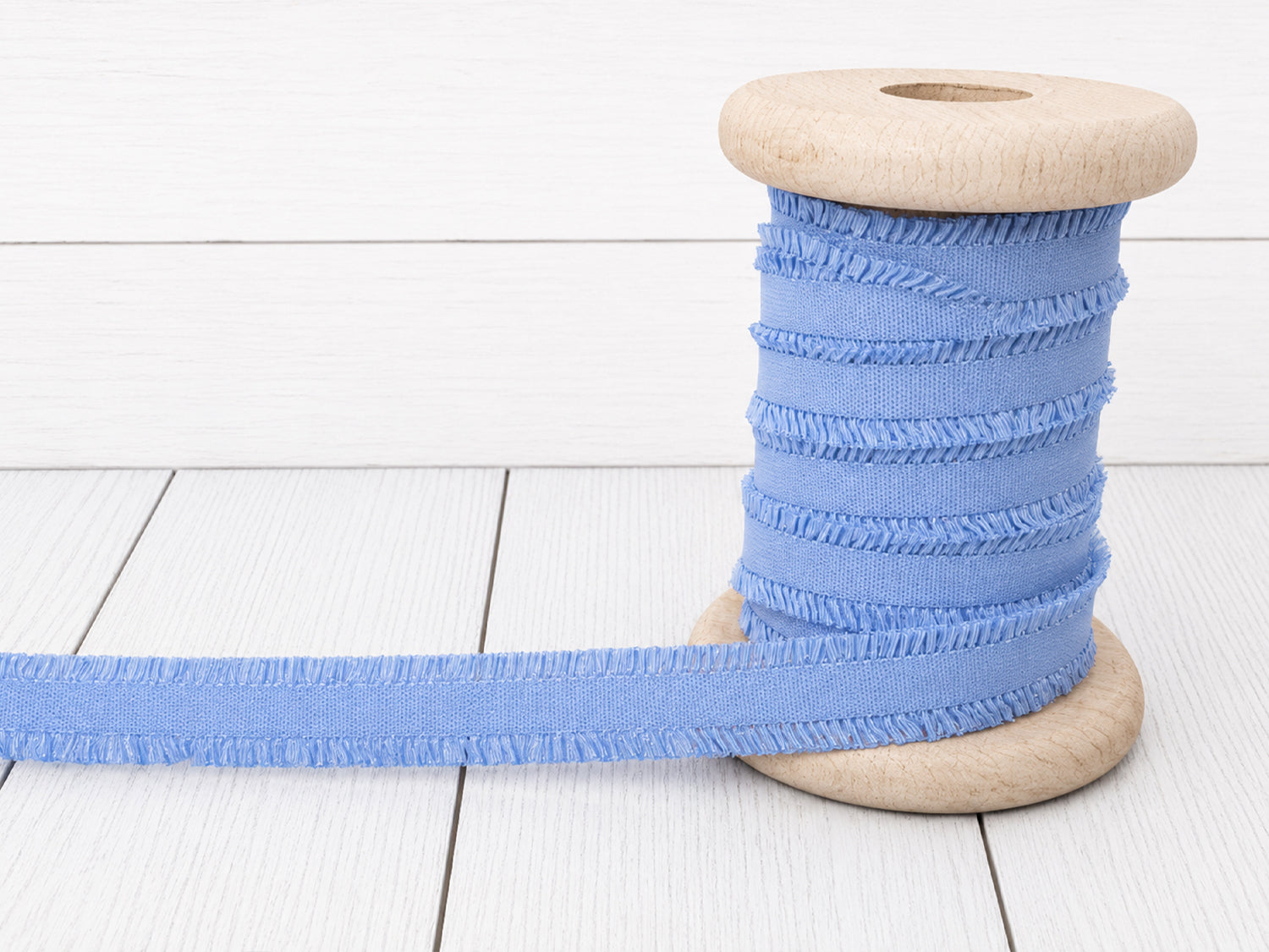 hellblau rüschen gummiband auf einer Holzspule, ideal für Nähprojekte und Verzierungen.