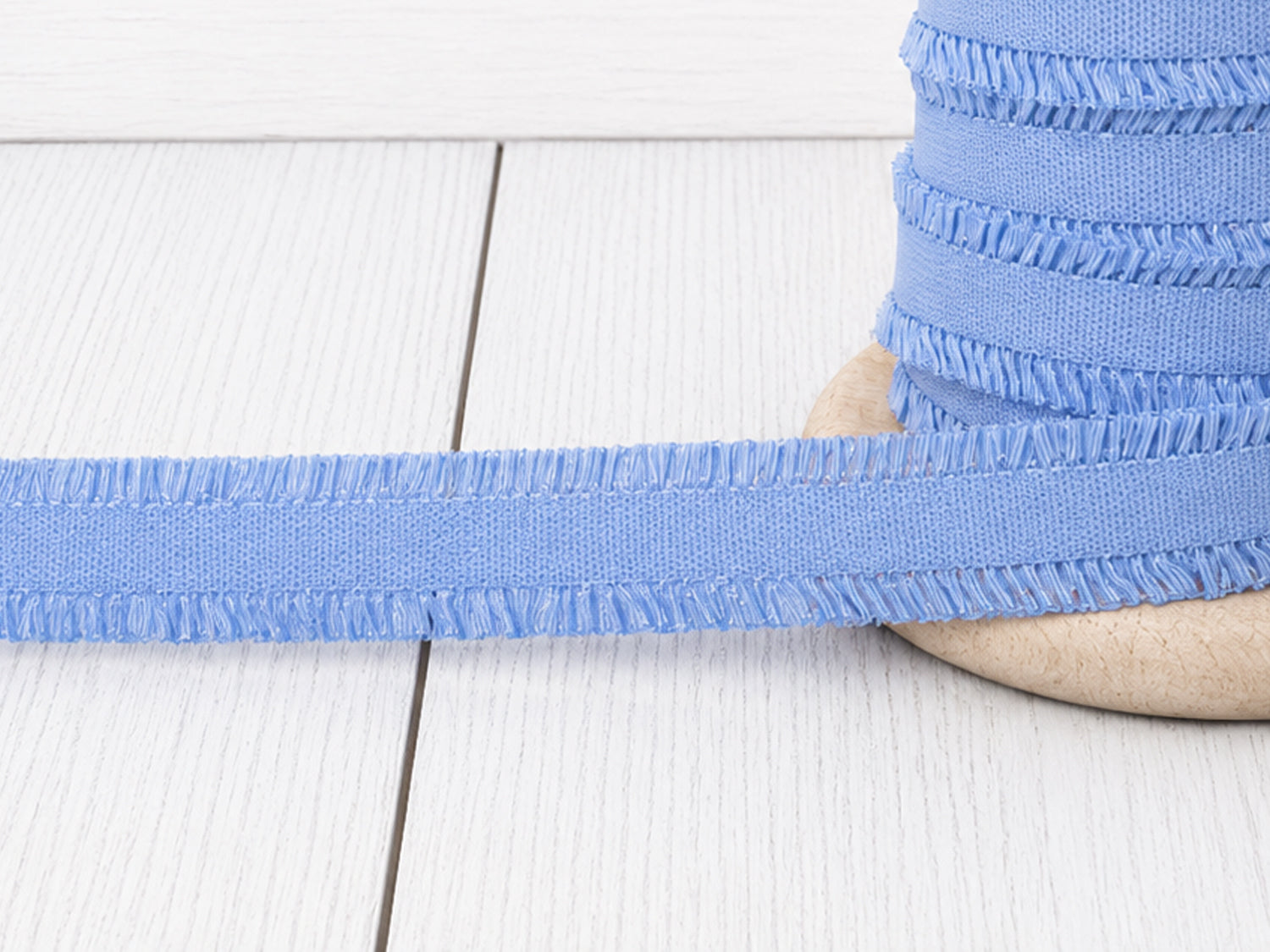 hellblau rüschen gummiband auf Holzoberfläche, ideal für Nähprojekte und Verzierungen.