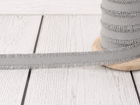 hellgrau rüschen gummiband auf einer Holzspule, ideal für Nähprojekte und Verzierungen.