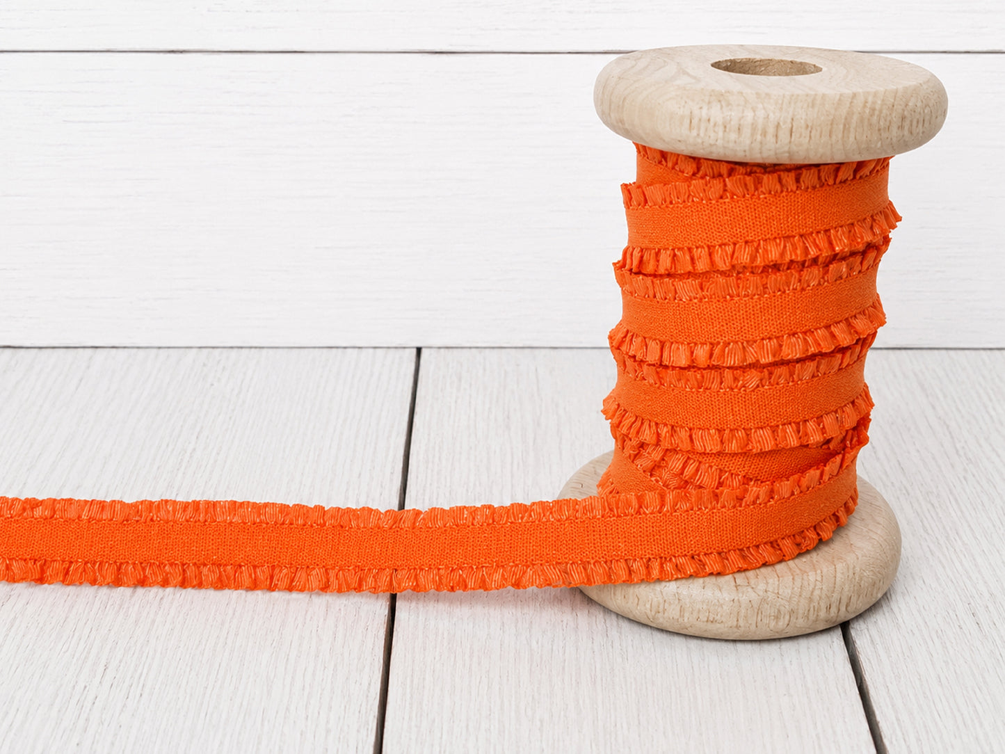 orange rüschen gummiband on a wooden spool, perfect for sewing projects and embellishments.