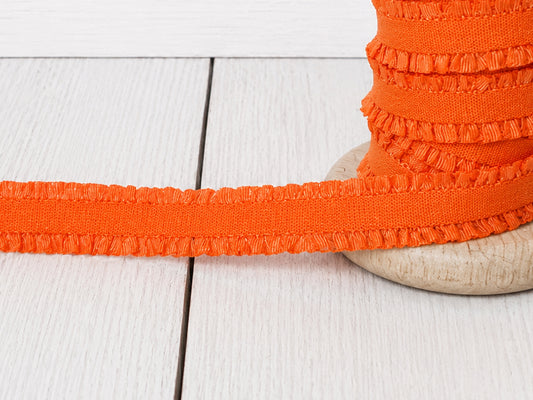 orange rüschen gummiband auf Holzspule für vielfältige Nähprojekte und kreative Bastelideen.