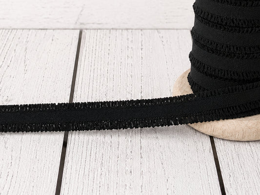 Schwarzes Rüschen Gummiband auf einer Holzspule, ideal für kreative Nähprojekte, aus 100% Polyester.