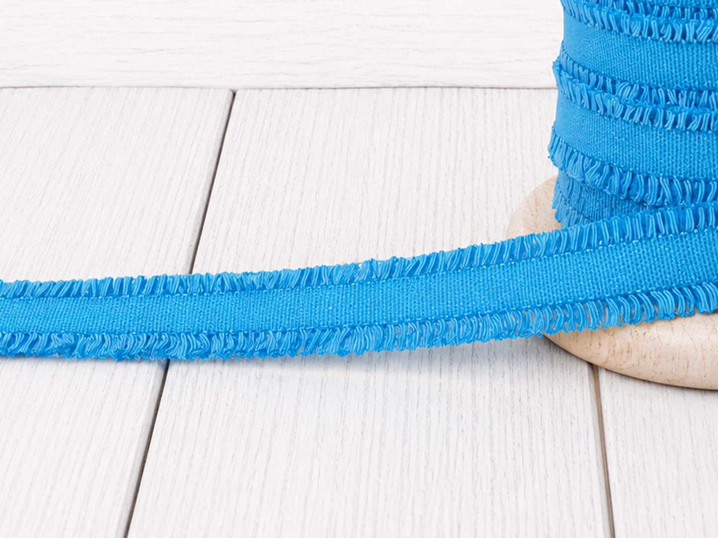 türkis rüschen gummiband auf Holzuntergrund, ideal für Nähprojekte und kreative Verzierungen.