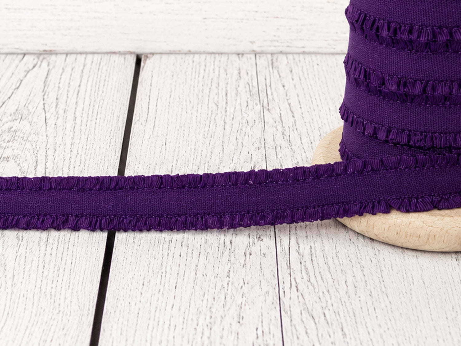 Violett Rüschen Gummiband auf Holzoberfläche, ideal für Nähprojekte und Verzierungen.
