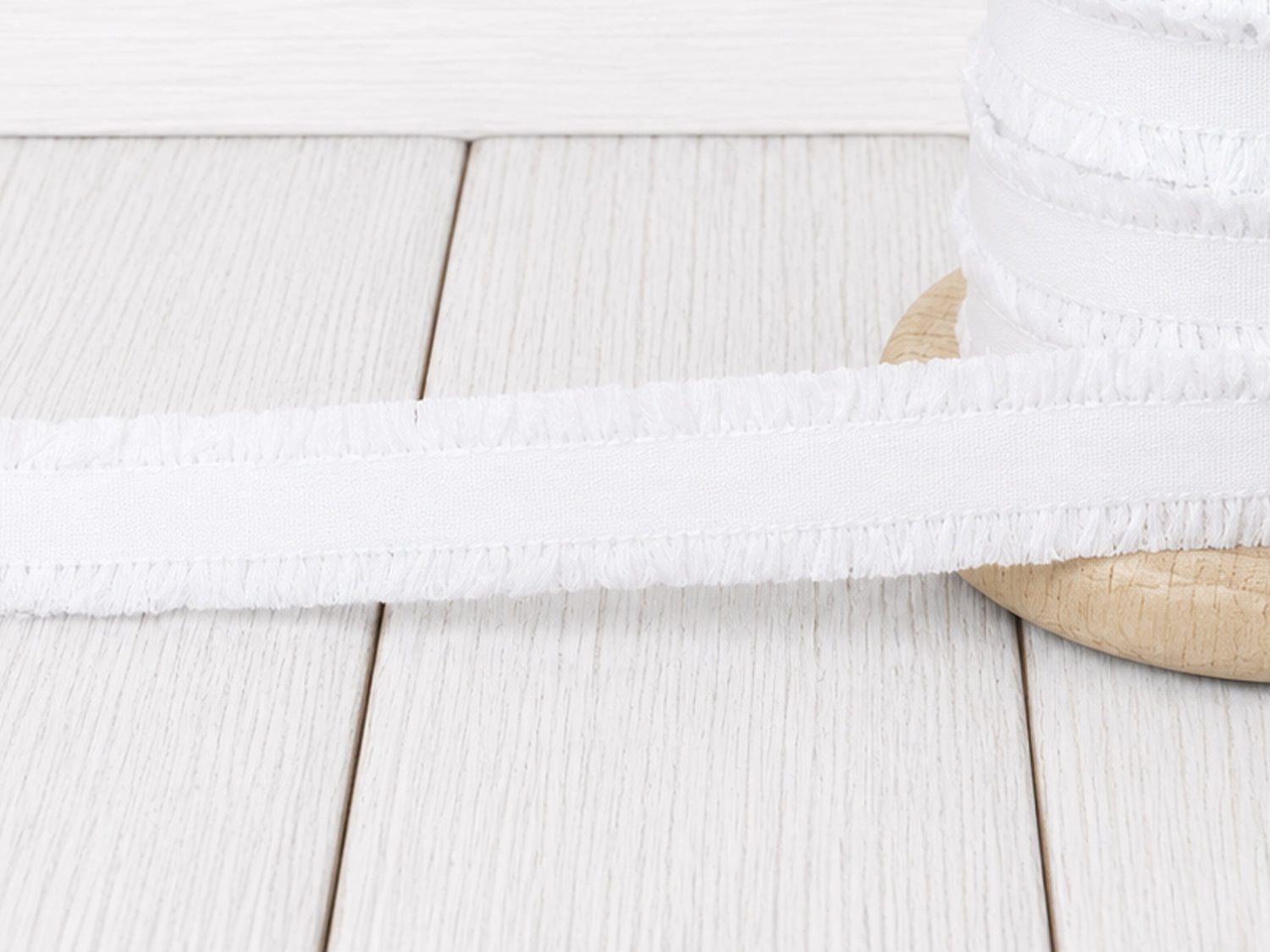 Rüschen Gummiband - weiß auf Holzuntergrund, ideal für Nähprojekte, jetzt weiss rüschen gummiband kaufen.