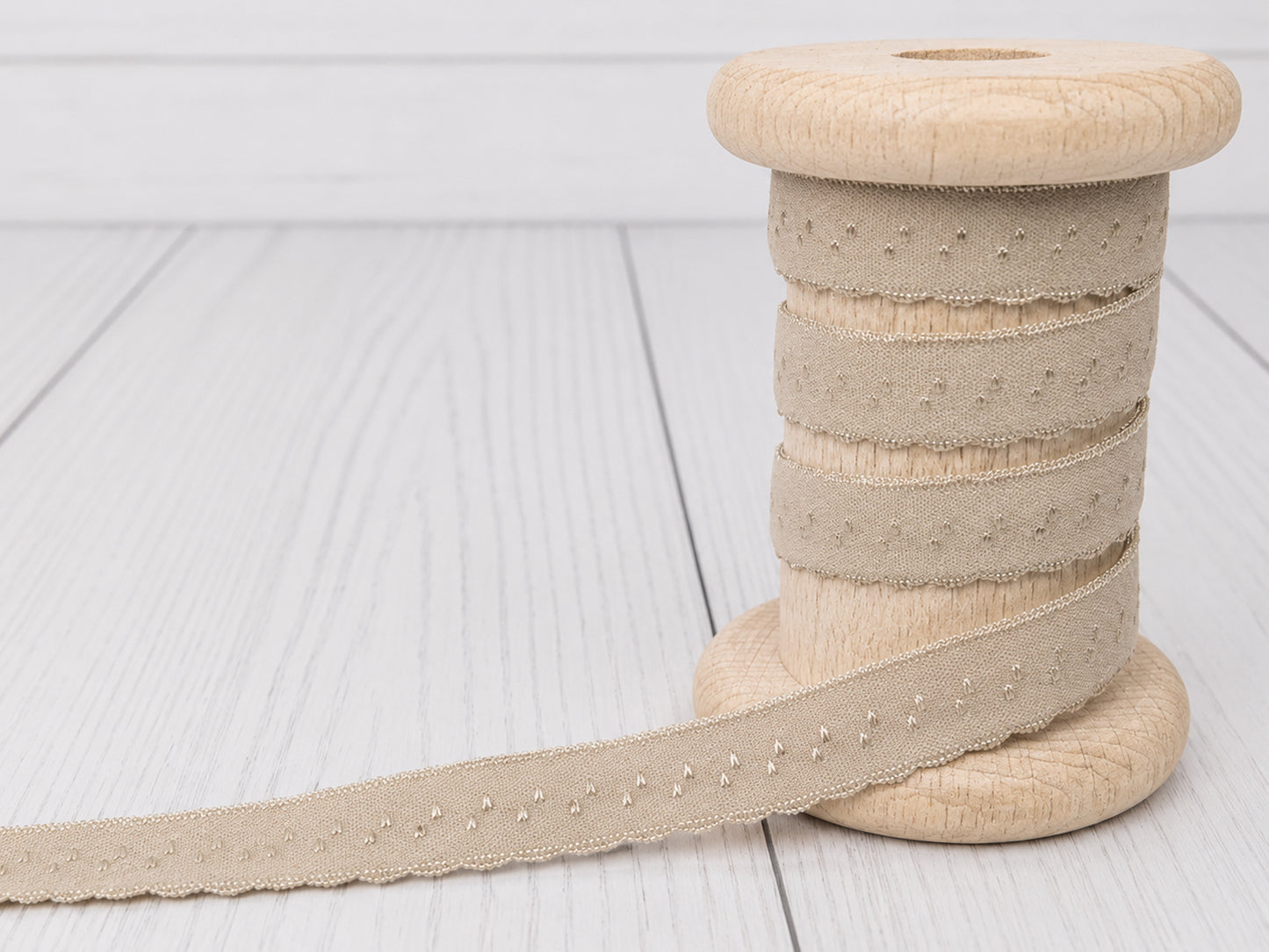 beige elastic bias tape on a wooden spool with decorative edge, ideal for sewing projects