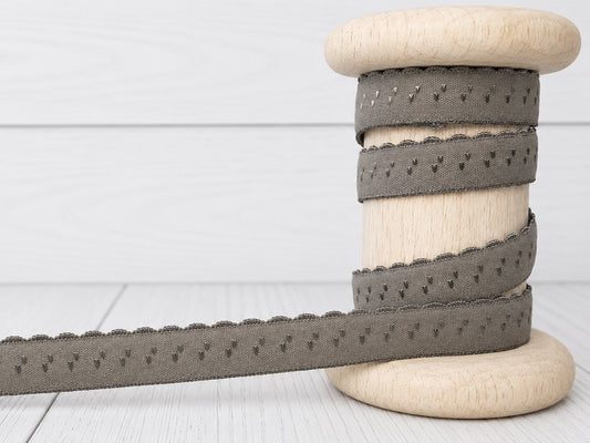 dunkles taupe elastisches Einfassband auf Holzspule, 11 mm breit, mit Bogenkante, 95% Polyamid, 5% Elasthan.