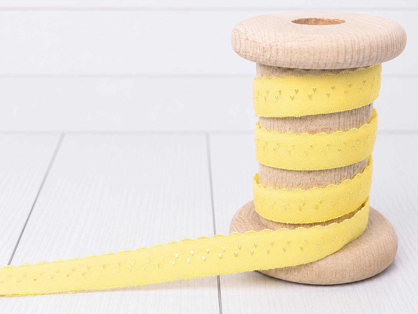 gelbes elastisches Einfassband auf einer Holzspule, ideal für Näh- und Bastelprojekte.