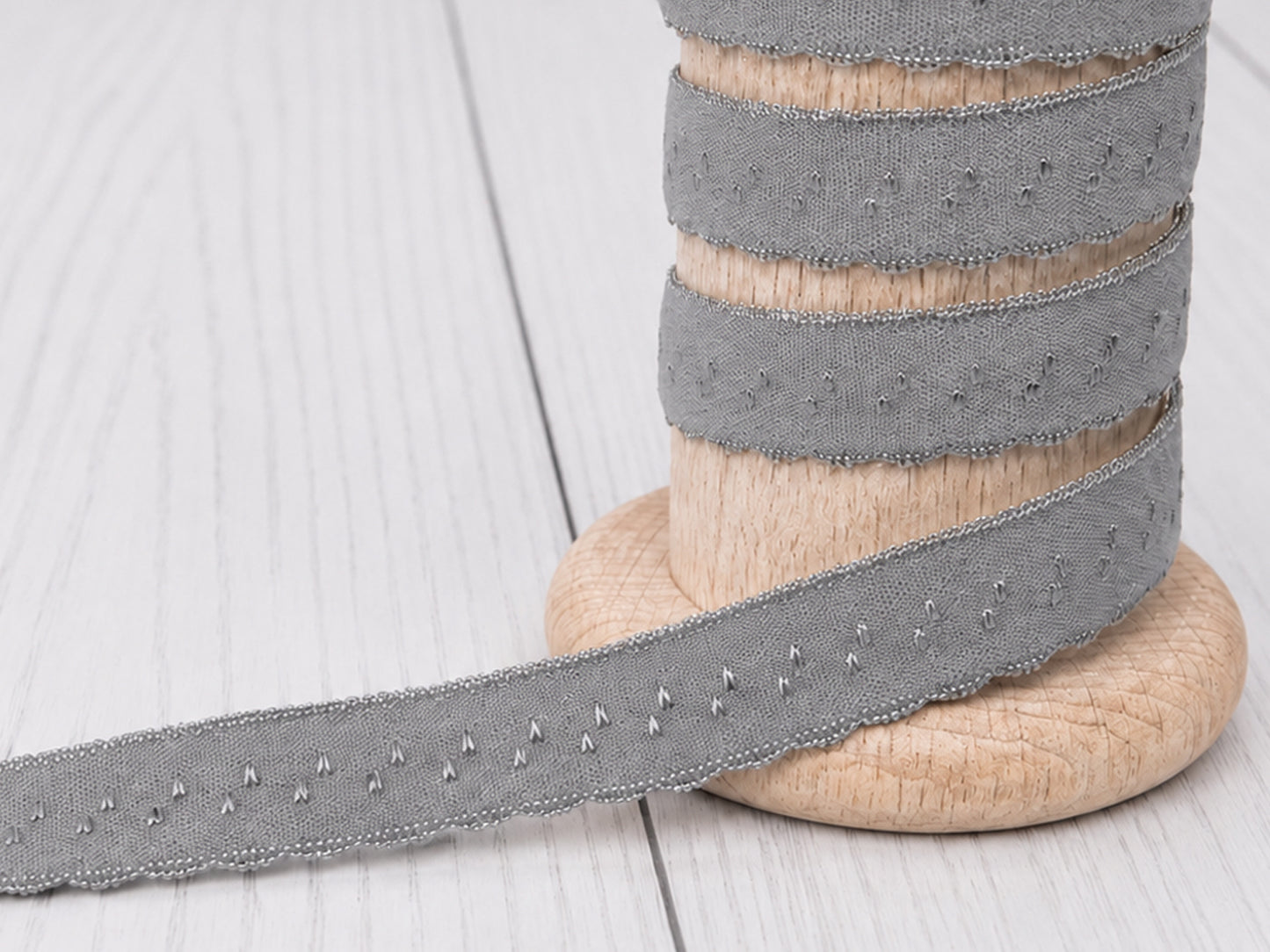 grau elastisches einfassband auf einer Holzspule, ideal für Nähprojekte und kreative DIY-Ideen.