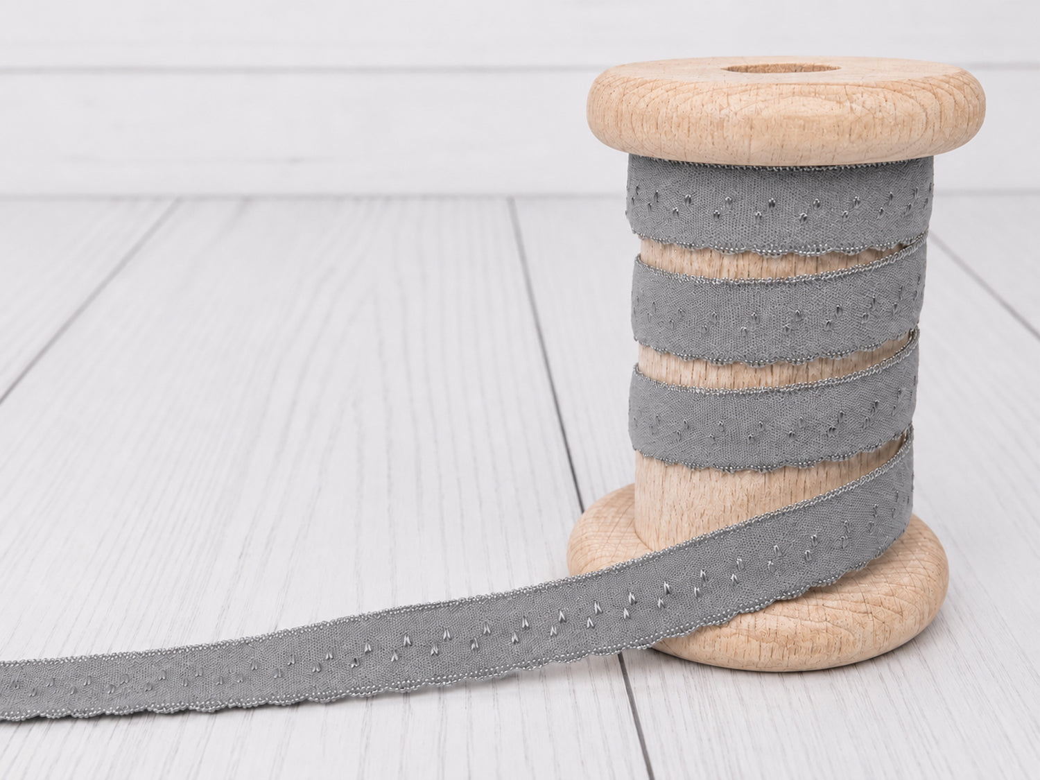 grau elastisches einfassband auf einer Holzspule, ideal für kreative Nähprojekte und Dekoration.