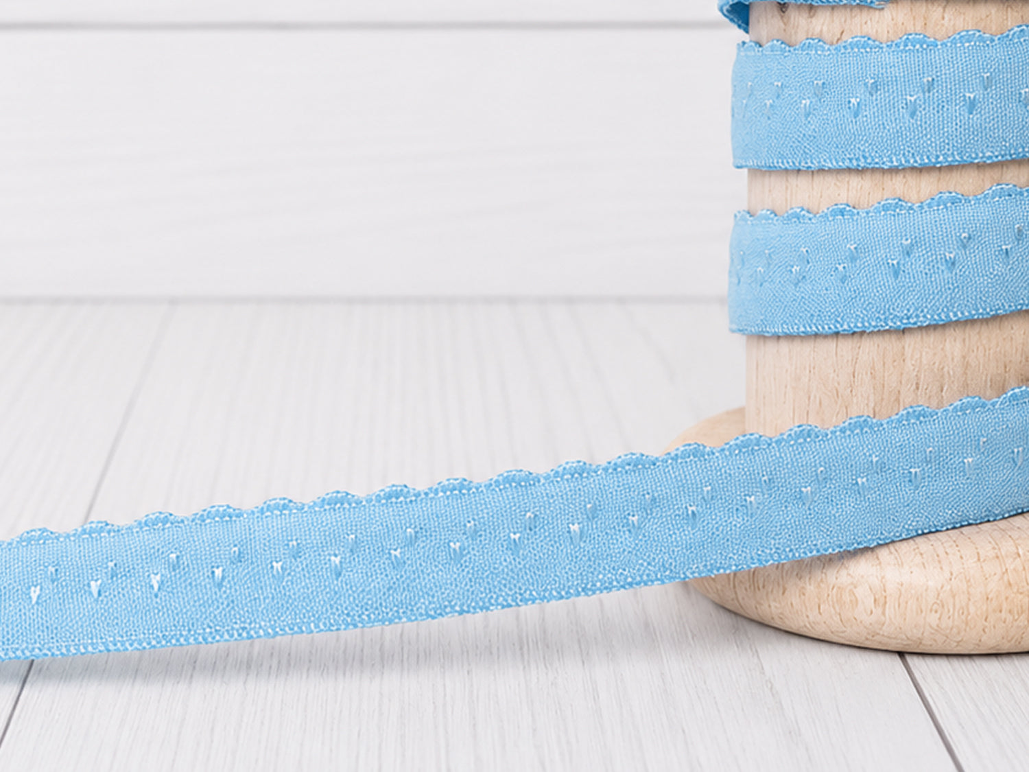 hellblau elastisches einfassband auf einer Holzrolle, ideal für Näh- und Bastelprojekte.
