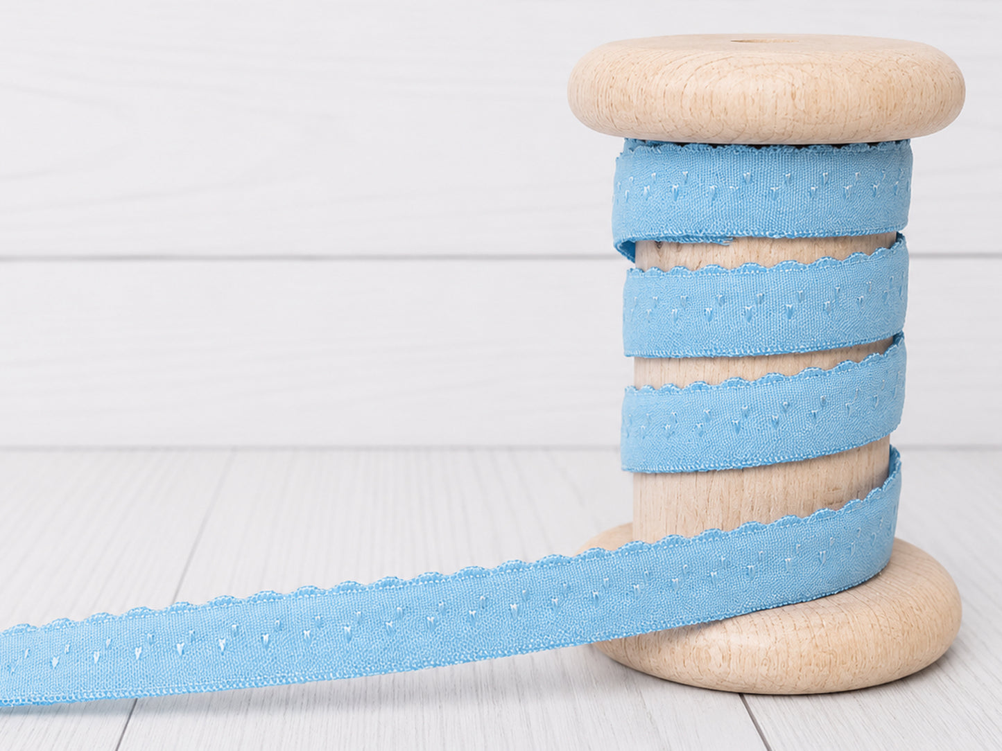hellblau elastisches einfassband auf einer Holzspule, dekoratives Design mit Bogenkante, 11 mm breit