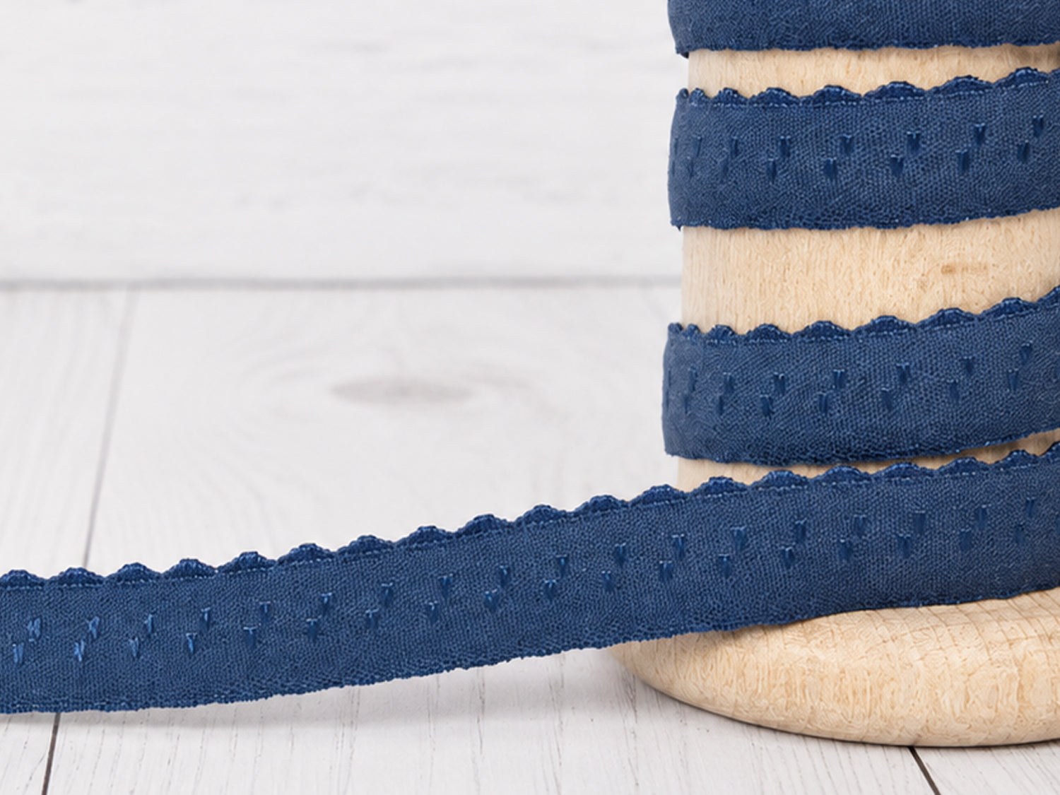 jeansblau elastisches einfassband auf einer Holzrolle, ideal für kreative Nähprojekte, ca. 11 mm breit.