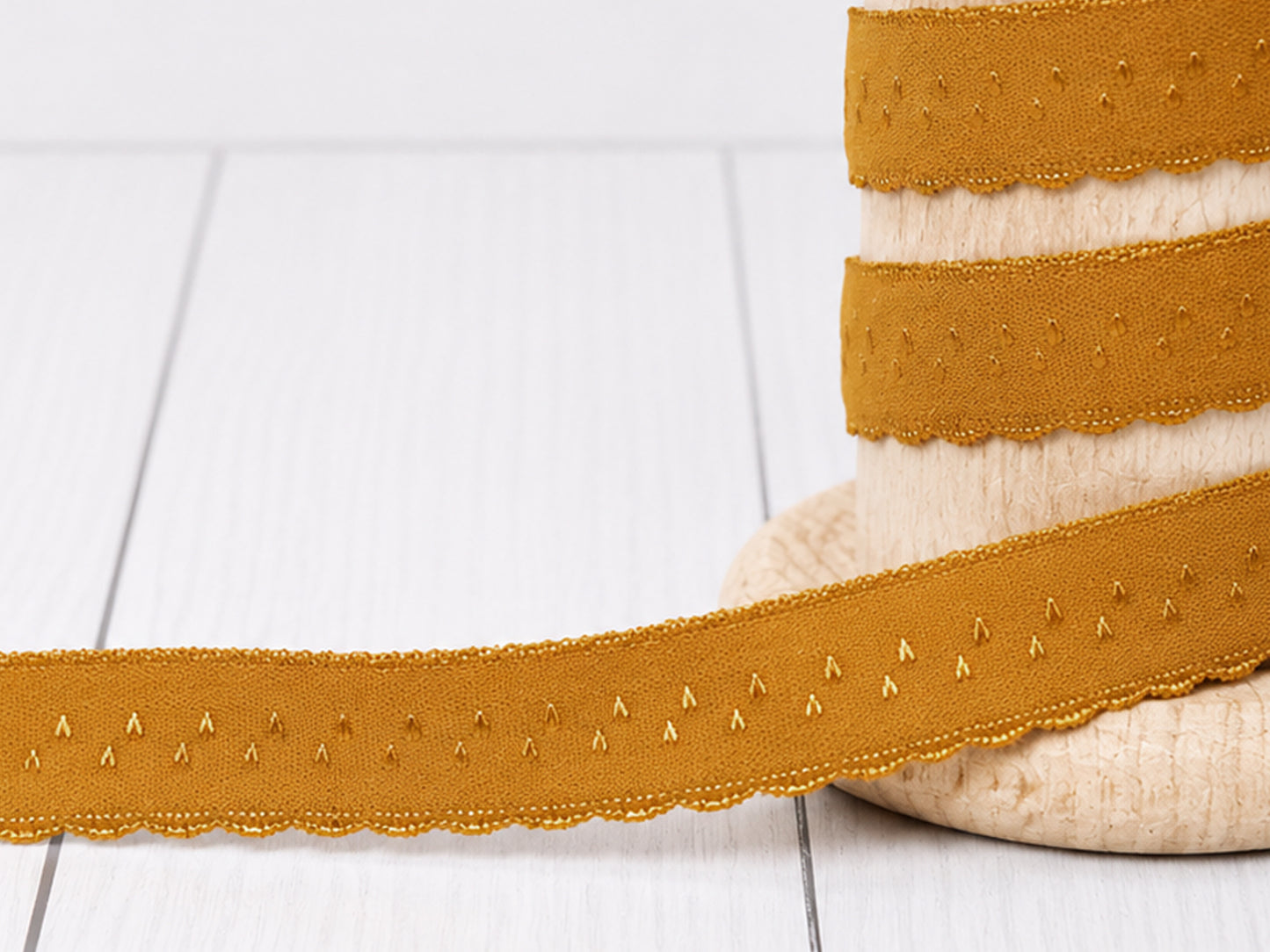 Elastisches Einfassband - ocker auf einer Rolle, gefertigt aus 95% Polyamid und 5% Elasthan.