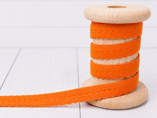 Elastisches Einfassband orange auf Holzspule, ideal für Nähprojekte und Dekoration.