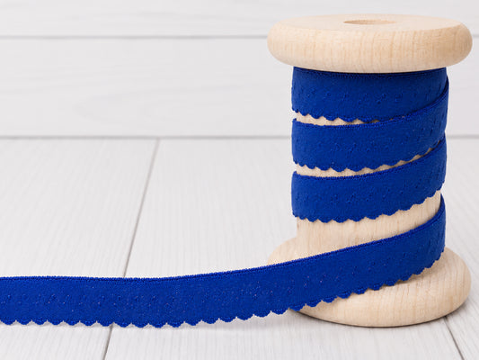 royal blue elastic binding tape on a wooden spool, showcasing its beautiful scalloped edge and vibrant color.