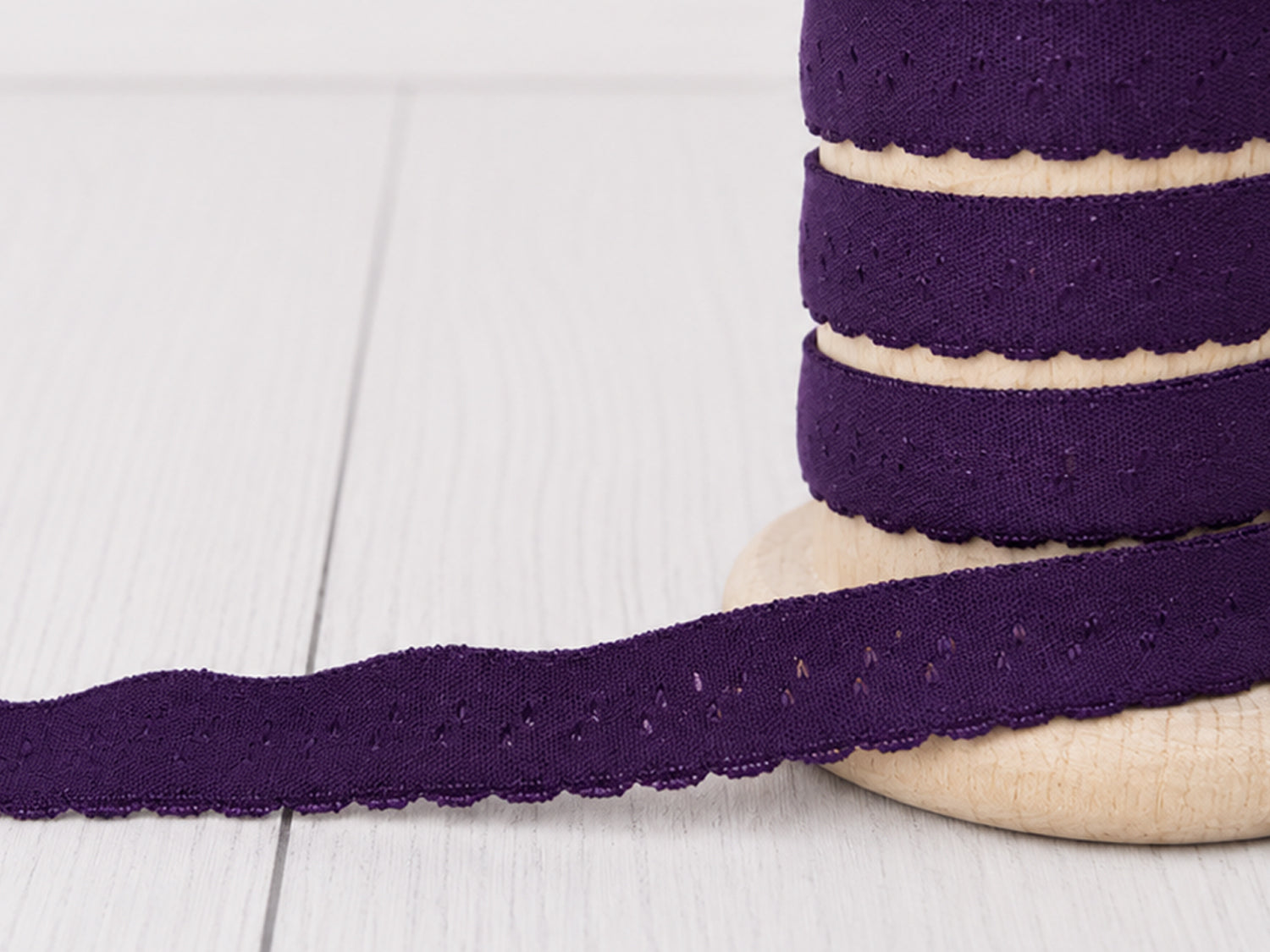 Elastisches Einfassband - violett in Bogenkante auf Holzspule, 11 mm breit, aus 95% Polyamid und 5% Elasthan.