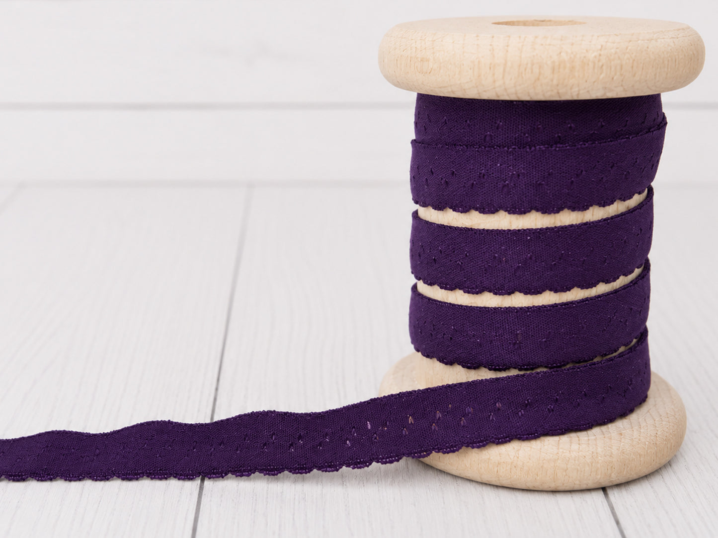 Elastisches Einfassband - violett auf einer Holzspule, ideal zum Nähen und Basteln.
