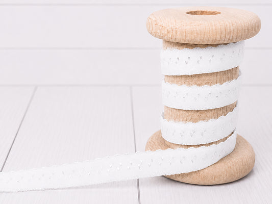 Elastisches Einfassband - weiß auf einer Holzspule, ideal für kreative Nähprojekte.