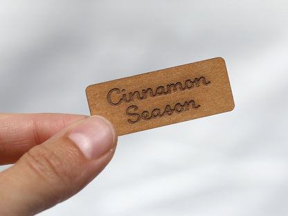cinnamon snap pap label held by a hand, featuring the text 'Cinnamon Season' on a leather-like brown material.