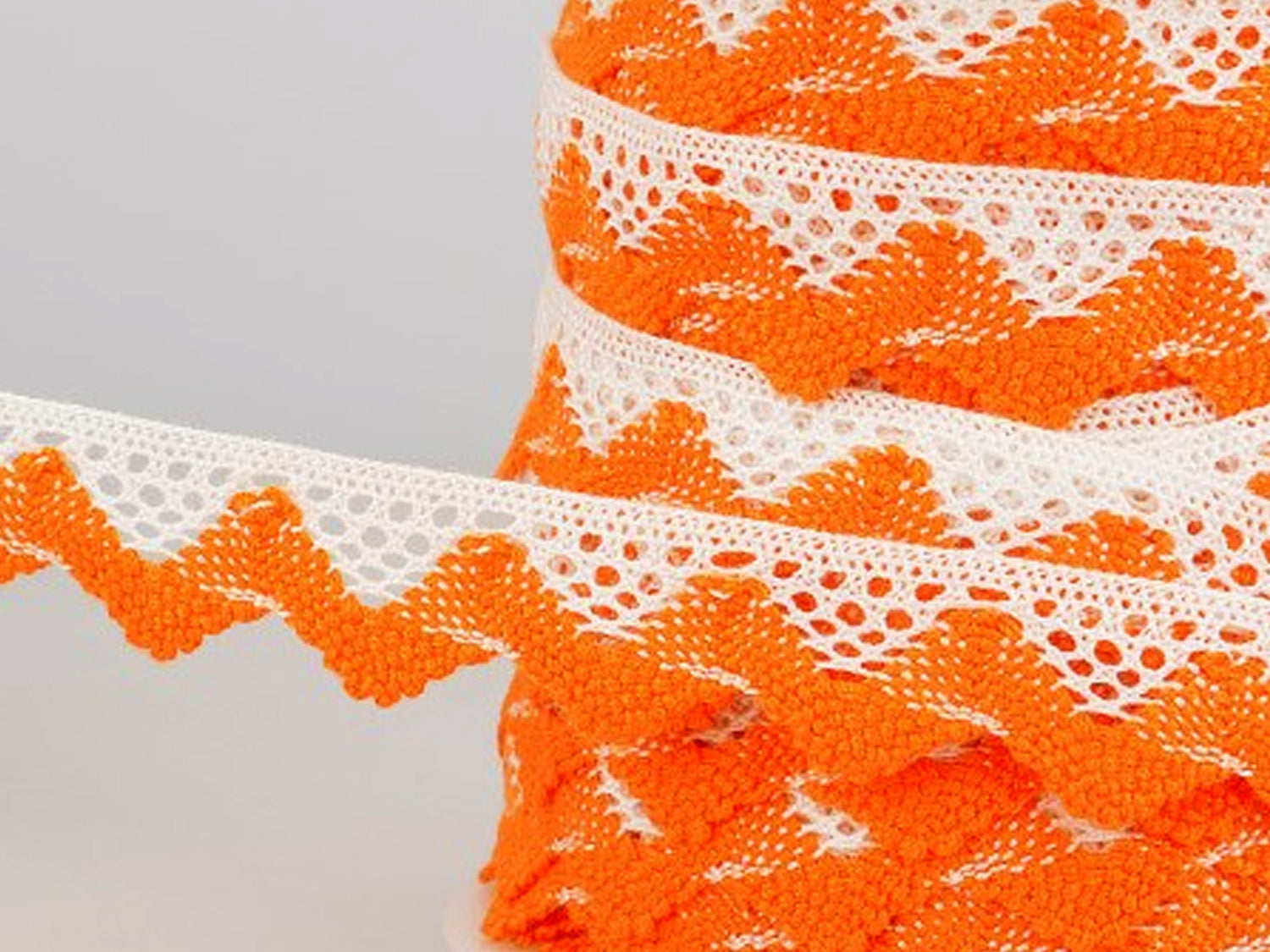 Zweifarbige Spitze 20mm orange weiß auf Rolle, ideal für Handarbeiten und Dekoration.