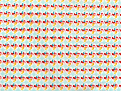 Patchworkstoff - Baumwolle Stoff - Pinwheel in buntem Muster mit roten, gelben und blauen Farben auf hellem Hintergrund.
