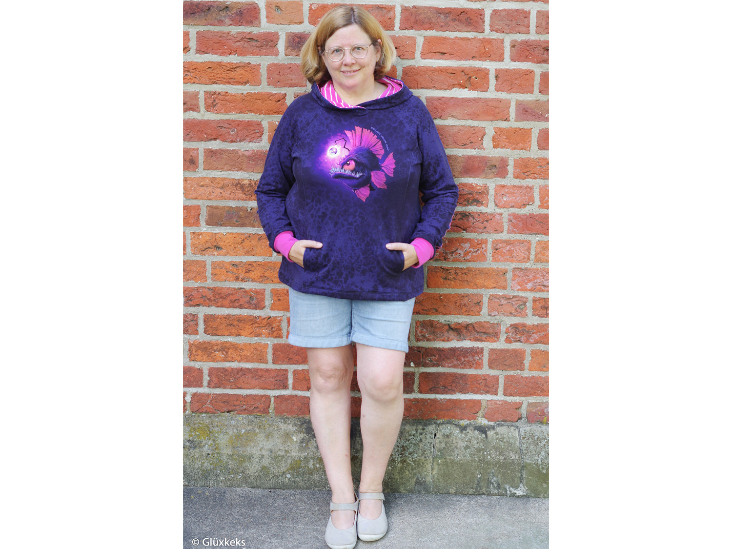 Model wearing French Terry PANEL - Thorsten Berger - Deep Water hoodie against a brick wall.