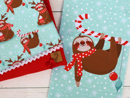 French Terry Merry Slothmas fabric panel featuring a cheerful sloth with a candy cane and playful reindeer patterns.