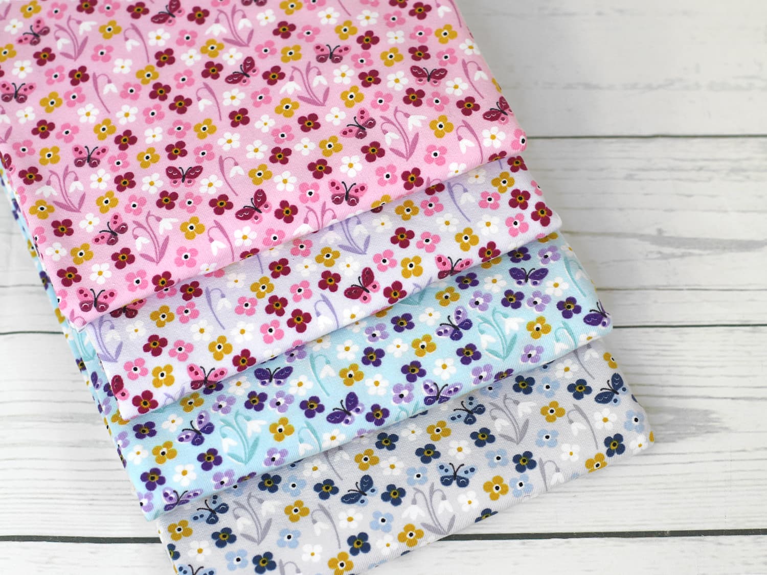 stoff-jersey-baumwolle-baumwolljersey-bluemchen-schmetterlinge-verschiedene-farben