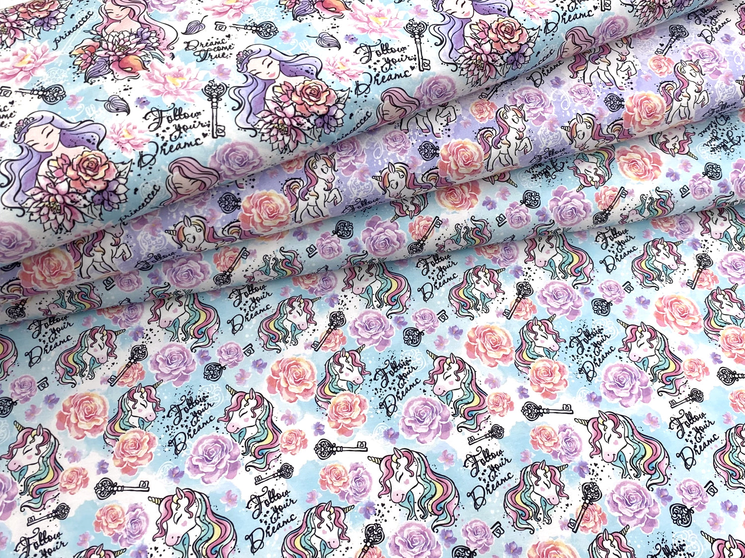 Jersey Stoff - Follow your Dreams - Prinzessin, helltürkis mit bunten Prinzessinnen und Blumen auf hellblauem Hintergrund.