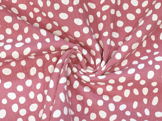altpink musselin fabric featuring playful white polka dots on a soft background.