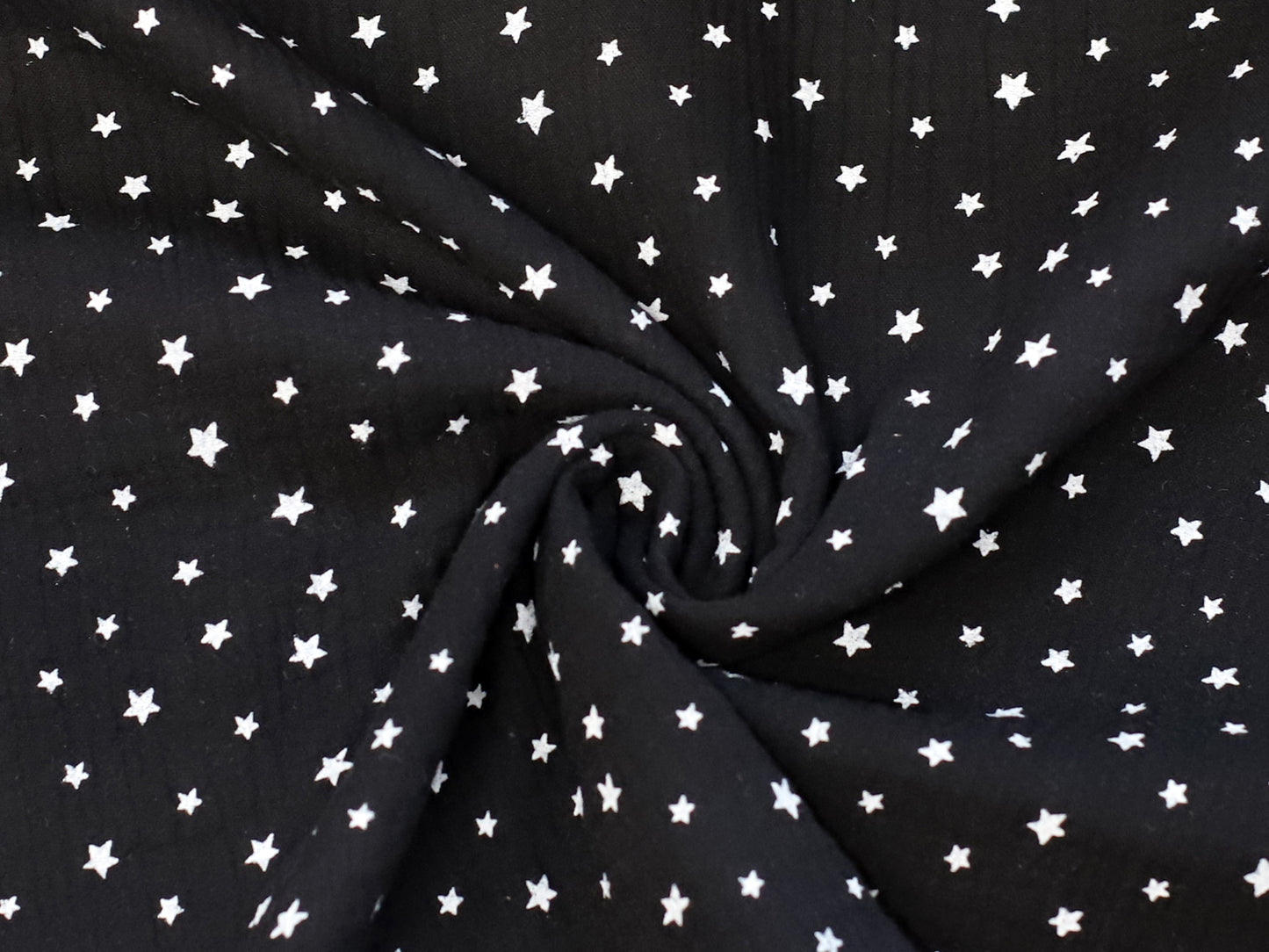 black star muslin fabric featuring a black background with white stars, perfect for various sewing projects.