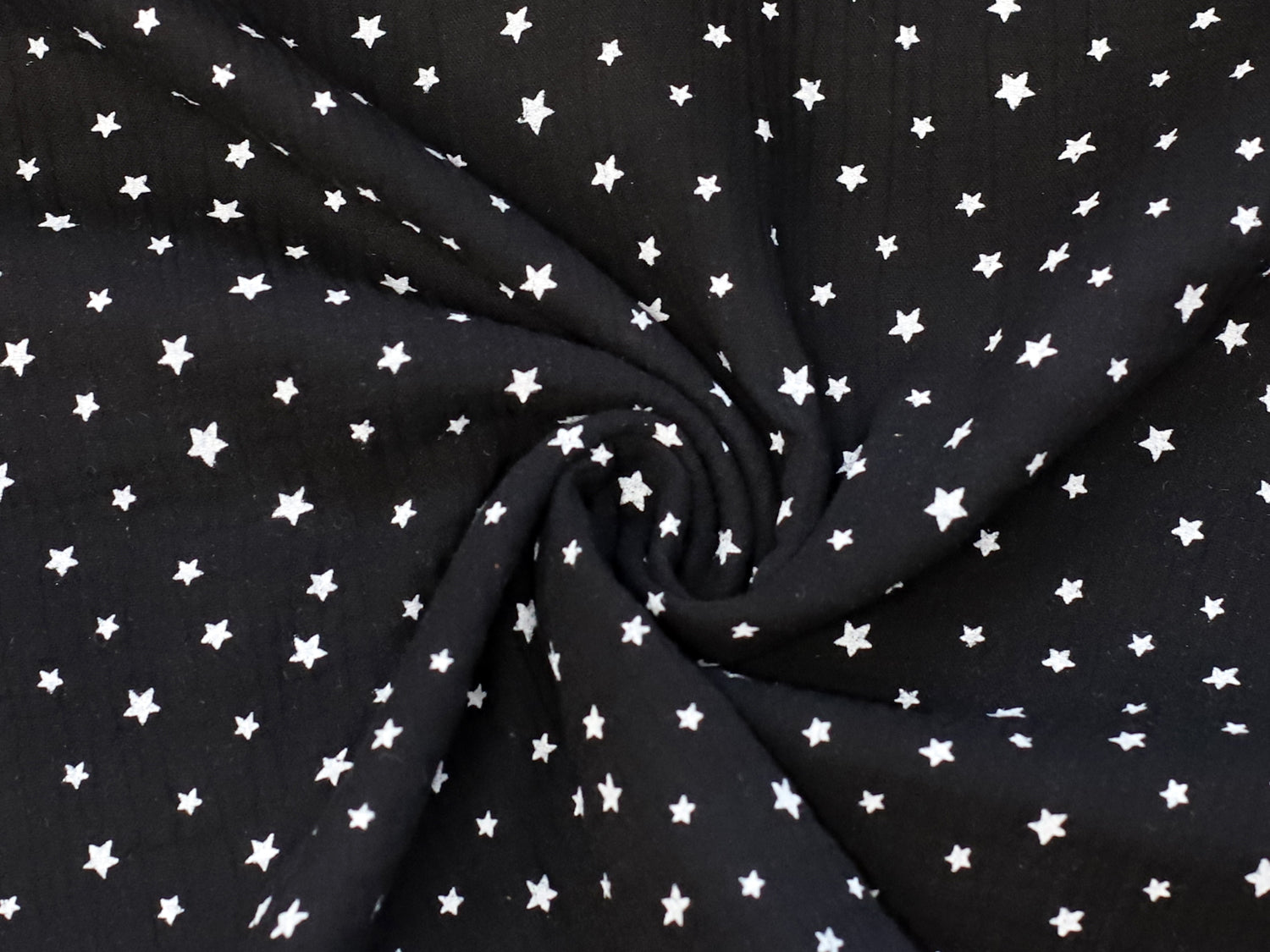 black star muslin fabric featuring a black background with white stars, perfect for various sewing projects.