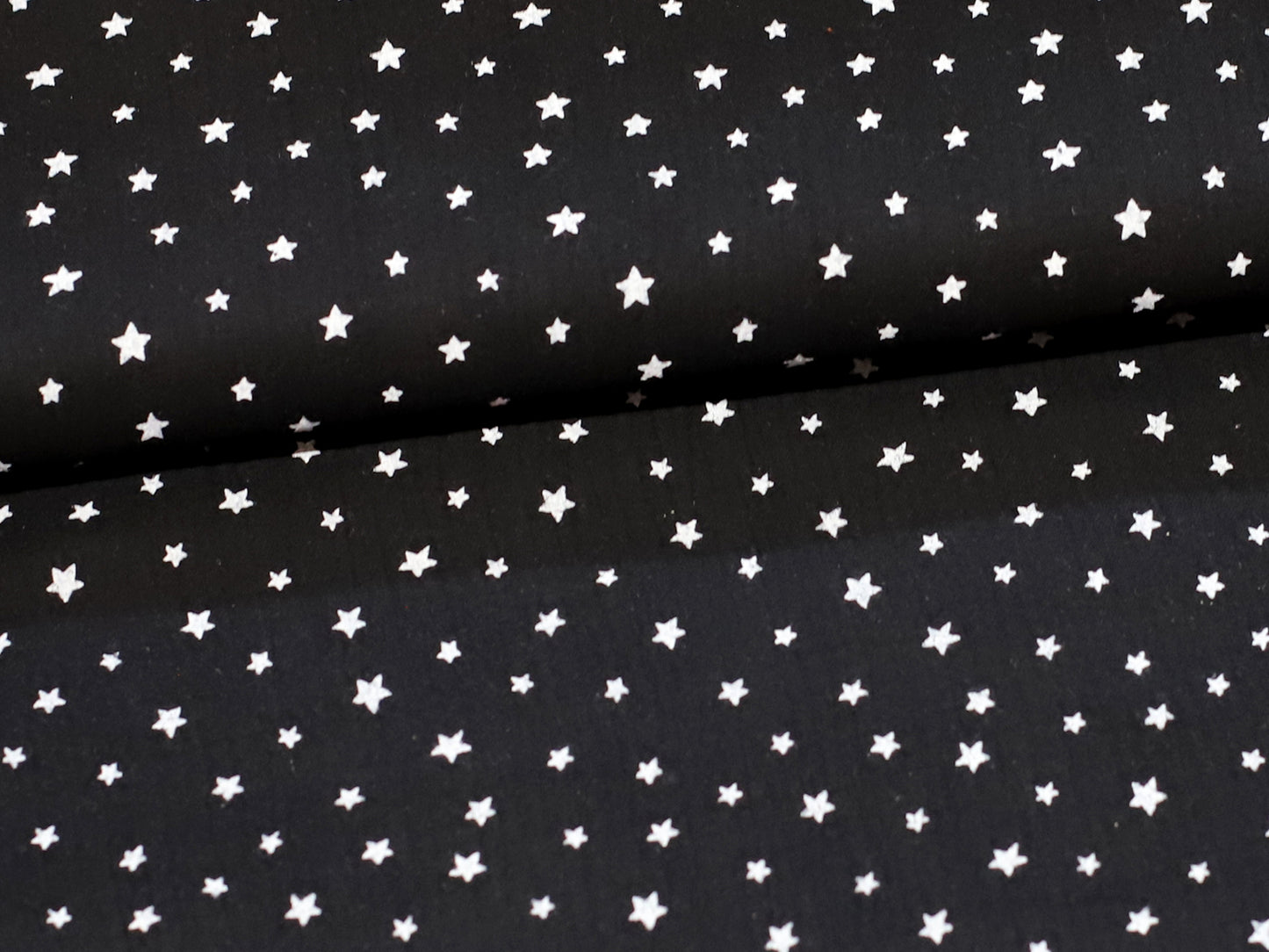 black star muslin fabric on a black background with white stars, perfect for sewing projects.
