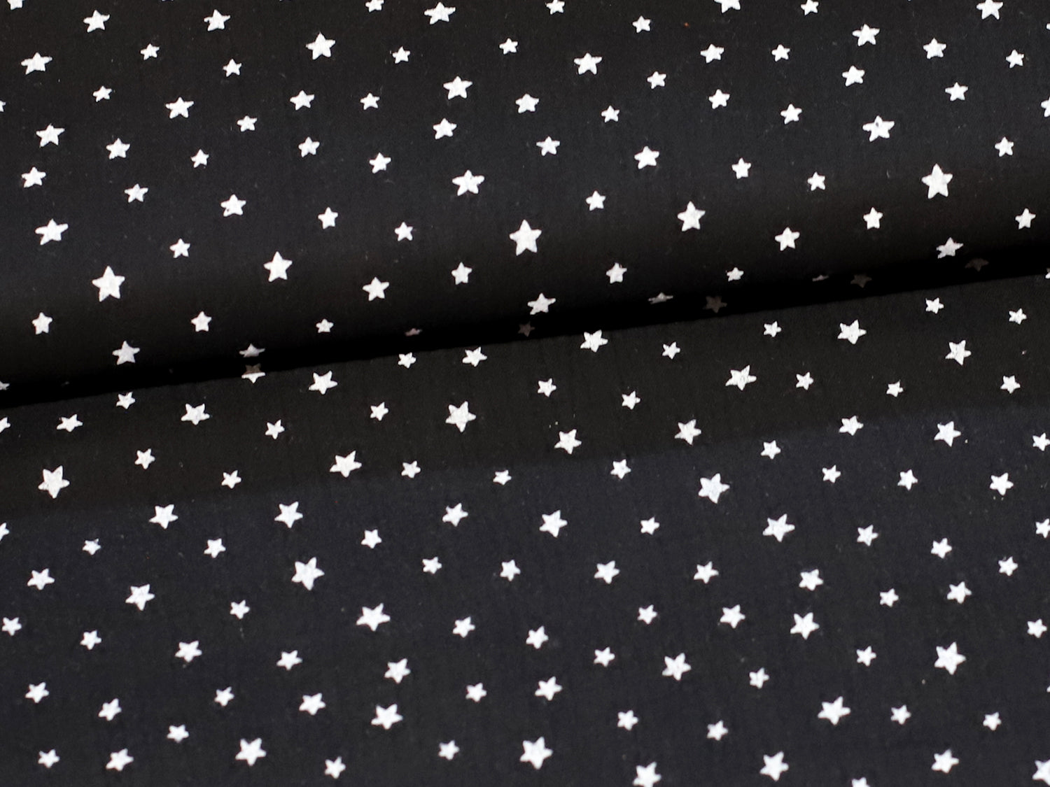 black star muslin fabric on a black background with white stars, perfect for sewing projects.