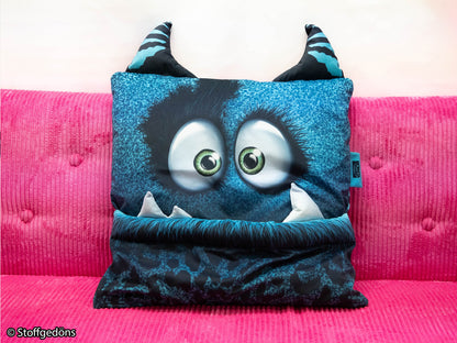Samt PANEL - Thorsten Berger - MONSTA KISSEN, petrol mit großen Augen und Monsterdesign auf einer pinken Couch.