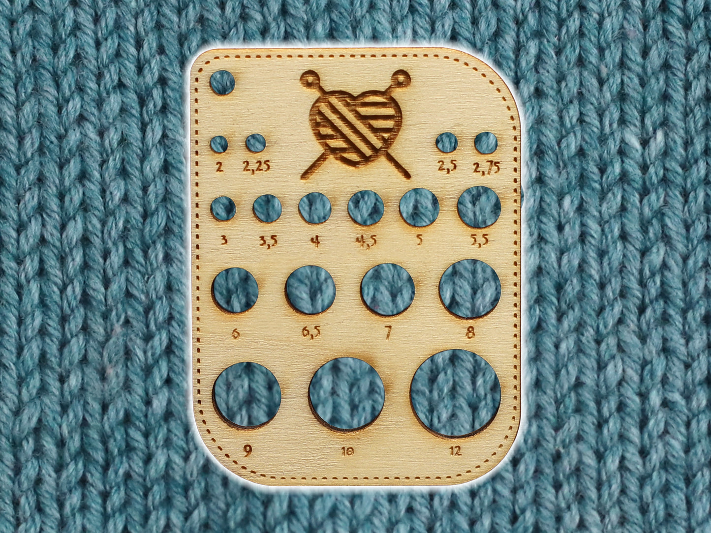 Kleines Nadelmaß für Stricknadeln aus Holz mit Größen von 2mm bis 12mm auf einem gestrickten Hintergrund.